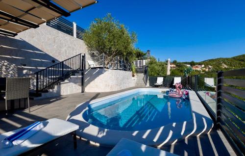 a swimming pool with chairs and a person in the water at Beautiful Home In Vrgorac in Vrgorac