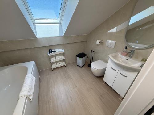 a bathroom with a sink toilet and a skylight at Apartments Puntamika in Zadar