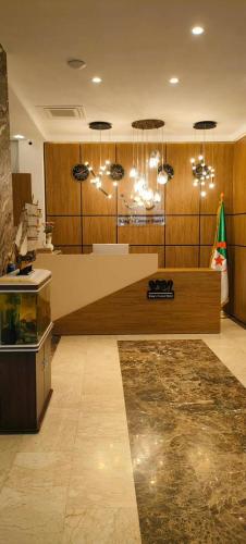 a lobby with a counter and chandeliers in a room at Hôtel Corner King in Skikda