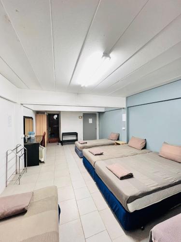 a large room with three beds and a table at Patong Adventure Hostel in Patong Beach