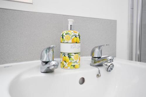 a bottle of alcohol sitting on a sink with two faucets at Stylish Durham 3-Bed Comfort Long Stays in Spennymoor