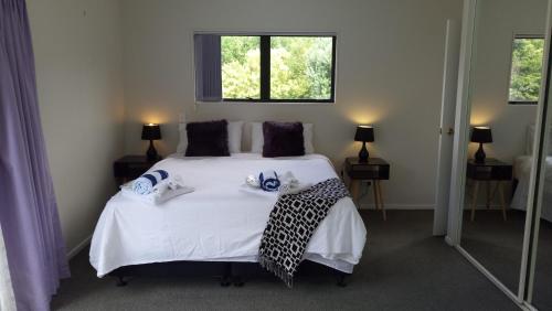 a bedroom with a bed with white sheets and a window at Sea La Vie in the Bays in Auckland