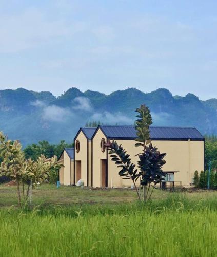 a large building in the middle of a field at Kiangnapa Cottage in Kanchanaburi City