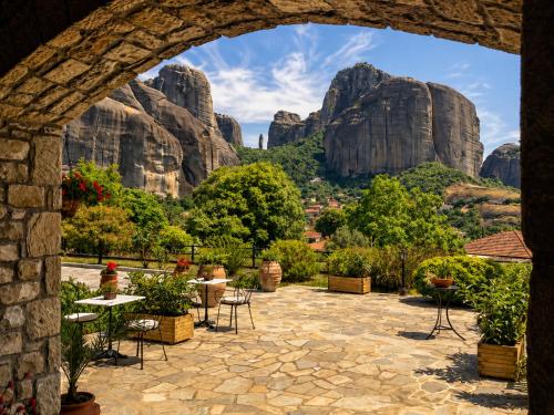 an archway with tables and chairs and mountains in the background at Hotel Doupiani House in Kalabaka