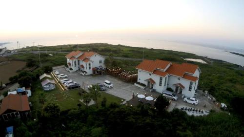 an aerial view of a house on a hill next to the ocean at Morning Beach Pension in Jeju