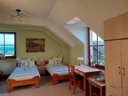 a room with two beds and a desk and a table at Agroturystyka Bobrowa Chata in Iława