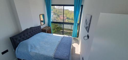 a bedroom with a bed and a large window at A dreamy luxury one-bedroom apartment with special views of the forest, sea and sunset in Alanya