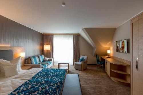 ヴィリンゲンにあるHotel Hochheideのベッドとリビングルームが備わるホテルルームです。