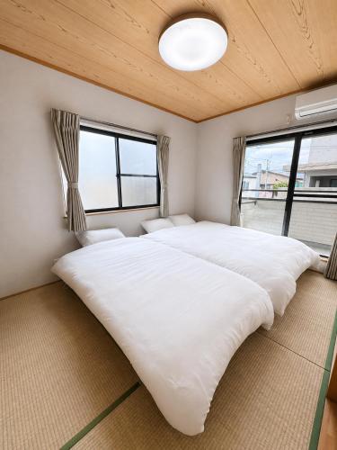 two beds in a room with two windows at Glad Kasuga in Kasugabaru