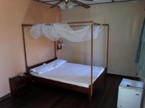 a bedroom with a canopy bed and a toilet at Hotel Valiha in Antsiranana