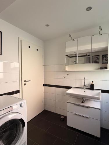 a white bathroom with a washing machine and a sink at Hermelsstübche in Siegen