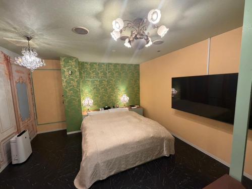 a bedroom with a bed and a flat screen tv at ホテル 天使と悪魔 in Gobō