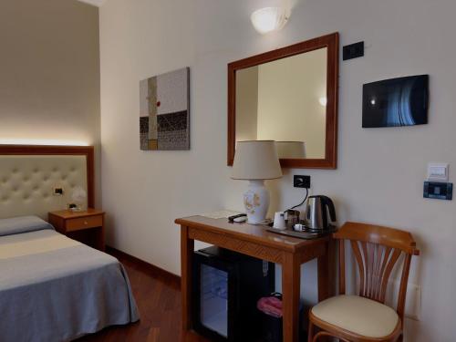 a bedroom with a bed and a table with a mirror at Hotel Del Corso in SantʼAntìoco