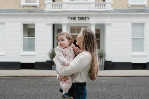 a woman holding a baby in front of the dry building at The Drey - Kensington, Earl's Court in London
