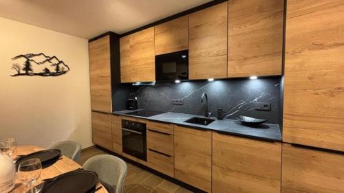 a kitchen with wooden cabinets and a sink at L Ecrin des Cimes 6 voyageurs in Arâches-la-Frasse