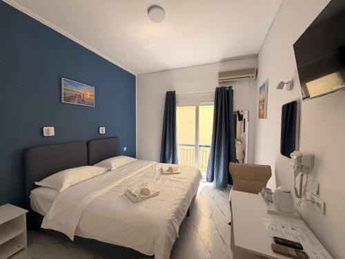 a bedroom with a bed with blue walls and a window at Hotel Avra in Egina