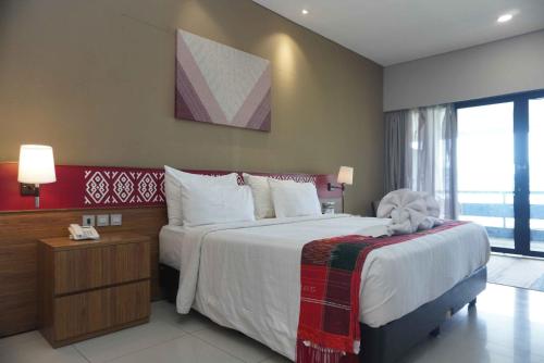 a hotel room with a large bed and a phone at Patra Parapat Hotel in Sibagading