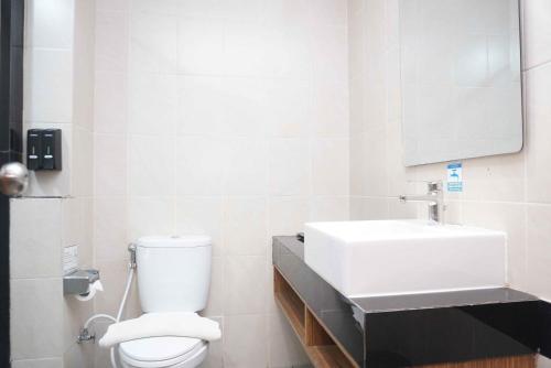 a bathroom with a white toilet and a sink at Patra Parapat Hotel in Sibagading