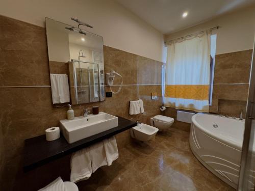 a bathroom with a sink and a tub and a toilet at Hotel Del Corso in SantʼAntìoco