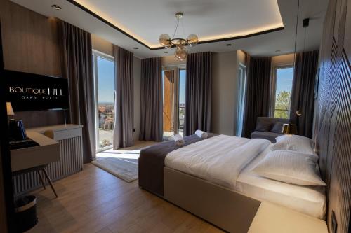 a bedroom with a large bed and a desk and windows at Boutique Hill Hotel in Požarevac