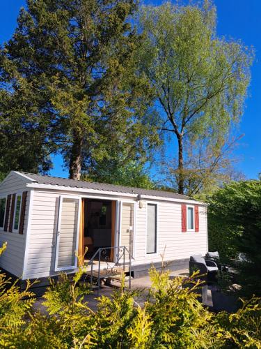 a white tiny house in a yard with trees at De Huisbij in Oude Willem