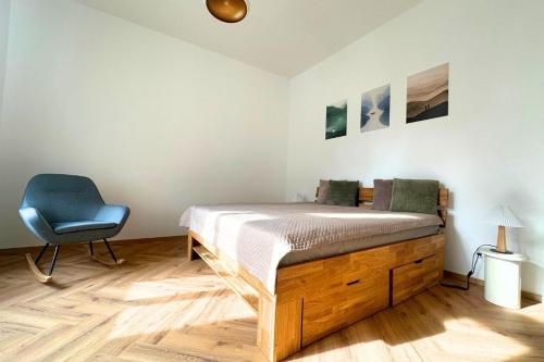 a bedroom with a bed and a blue chair at Elbe Stay Roudnice in Roudnice nad Labem