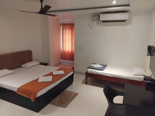 a bedroom with two beds and a desk and a window at Pibo Homestay in Port Blair