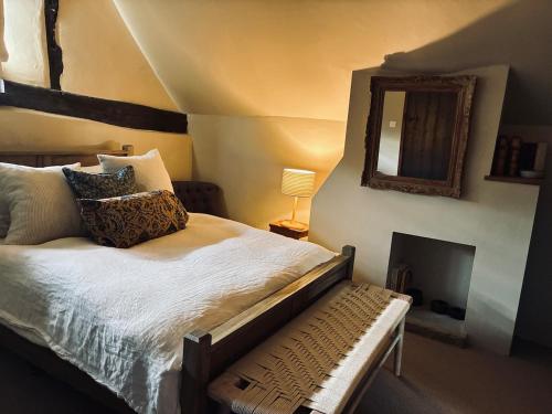 a bedroom with a bed with a mirror and a chair at Cottage in the Hambleden Valley in Henley on Thames