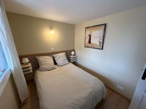 a bedroom with a bed and a picture on the wall at Logement indépendant avec jardin in Beaune