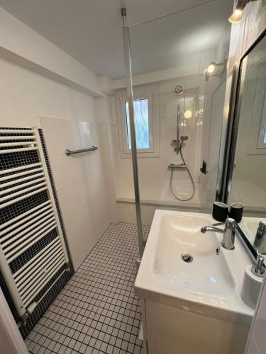 a white bathroom with a sink and a shower at Logement indépendant avec jardin in Beaune