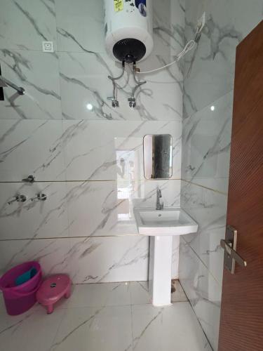 a white bathroom with a sink and a light at Deep Heritage Hotel & Restaurant in Phata
