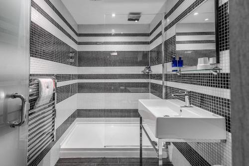 a black and white bathroom with a sink and a tub at Stay Central Hotel in Edinburgh