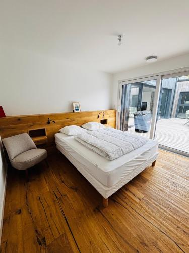 a bedroom with a large bed and a chair at Villa Wax - Piscine et plage in Santec