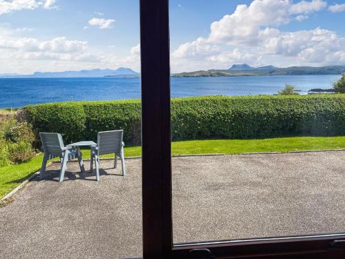a table and chairs with a view of the water at Kildonan in Laide