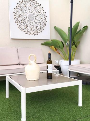a white coffee table with a vase and a bottle of wine at Cozy & Terrace Apartament5 in Los Cristianos