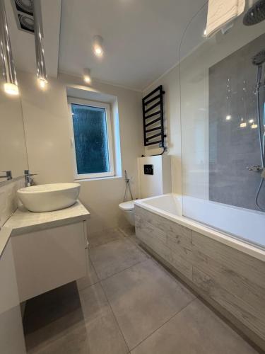 a bathroom with a tub and a sink and a bath tub at Apartament Wczasowa 3 in Sarbinowo