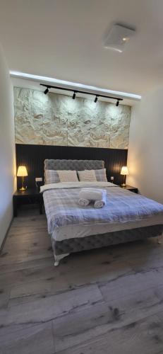 a bedroom with a large bed with a stone wall at Apartmani Banja Vrujci Lux in Gornja Toplica