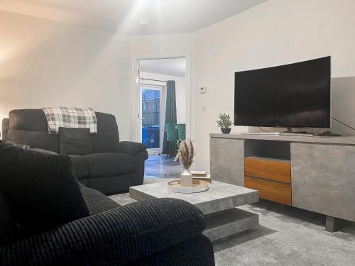 a living room with two chairs and a flat screen tv at Spring Gardens in Lower Darwen