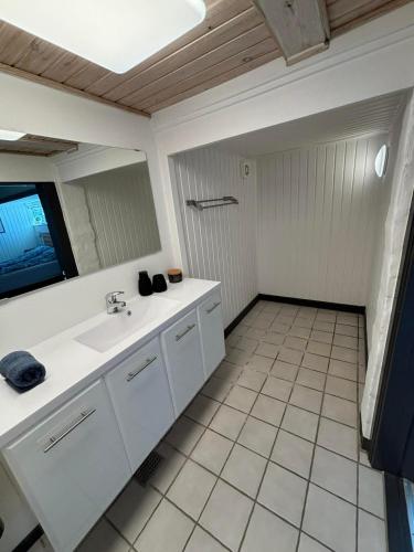a white bathroom with a sink and a mirror at H. C. Lumbyes Vej - kælderlejlighed in Odense