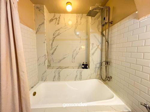 a bathroom with a bath tub with a marble wall at White Villa in General Santos