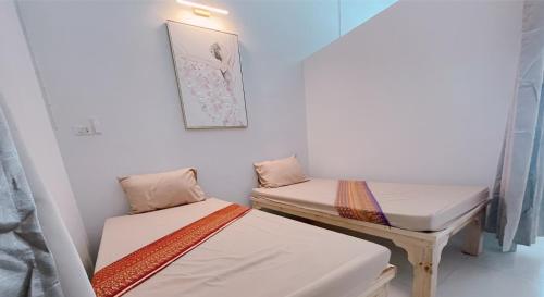 two twin beds in a room with a picture on the wall at latitude 14 Room & breakfast in Ban Bang Sakae
