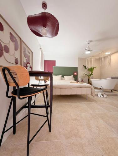 a bedroom with a bed and a desk and a table and chair at La Suite Bohème Émeraude in Évreux