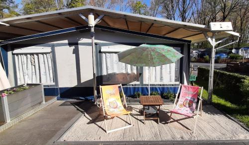 a pavilion with two chairs and an umbrella at Comtesse-Camping Plauer See in Brandenburg an der Havel