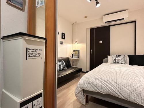 a bedroom with a bed and a tv and a couch at Mori de house in kobe 302 in Kobe