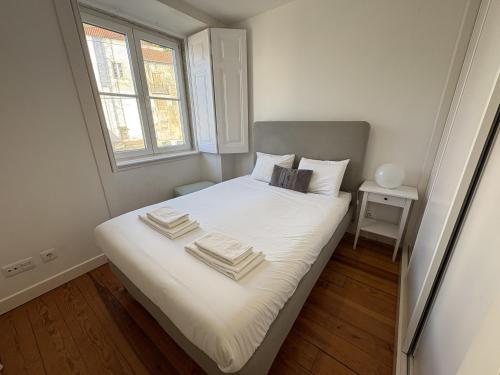 a bedroom with a bed with white sheets and a window at Alfama Premium in Lisbon