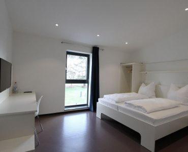 a white bedroom with a bed and a window at Neumann's Übernachtung in Plankstadt