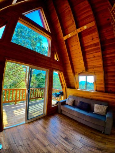 a living room in a tree house with large windows at Glamping MORET Cabaña Alpina M2 in Los Lirios