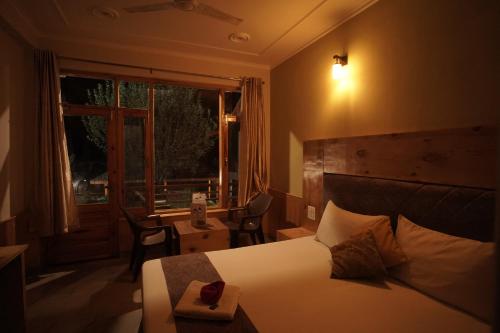 a hotel room with a bed and a window at Mountainshack Riverside Stay & Cafe in Kulu