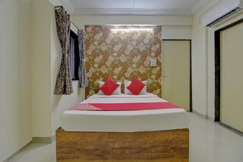 a bedroom with a large bed with red pillows at Hotel O Sai Executive Lodging in Māngvādi