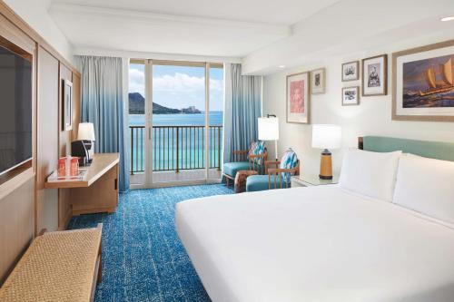a hotel room with a bed and a view of the ocean at OUTRIGGER Reef Waikiki Beach Resort in Honolulu